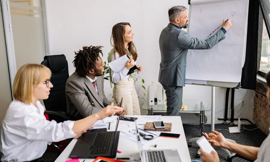 A team in a workshop meeting while a colleague writes on a flip chart