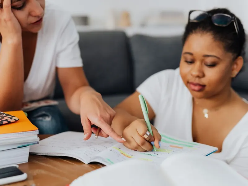 A tutor pointing out a section of a notebook to a student during a one-to-one session